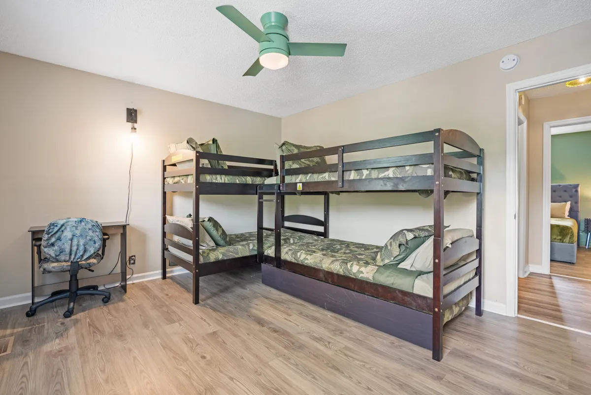 A practical and cozy bedroom setup with bunk beds, a desk, and a ceiling fan. The arrangement supports both restful nights and productivity, accommodating teams or groups on work trips.
