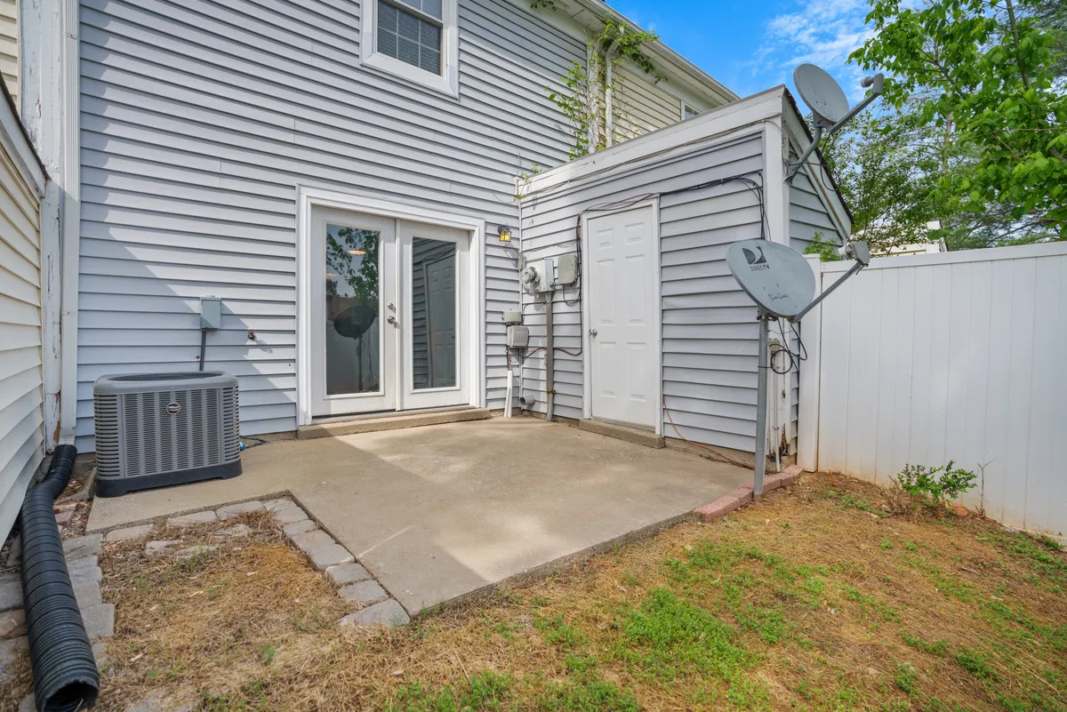 This exterior shot focuses on a casual patio area with sliding glass doors, satellite dishes, and an air conditioning unit. The space is designed for outdoor dining, relaxation, or enjoying the fresh air after a day at Fort Campbell or local attractions.