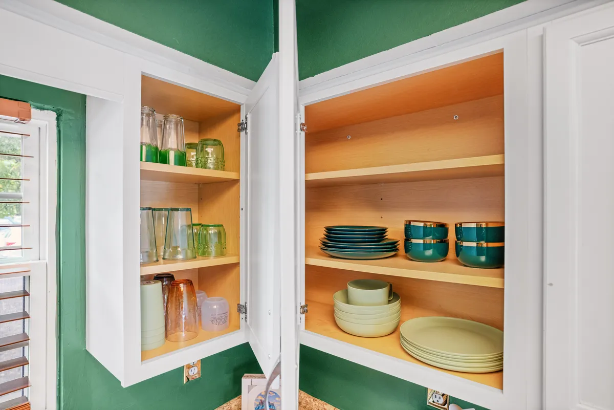 Open shelving filled with colorful dishes and glassware creates a warm, welcoming kitchen scene. The combination of wooden shelves and artfully arranged table settings invites guests to share meals and create new traditions.