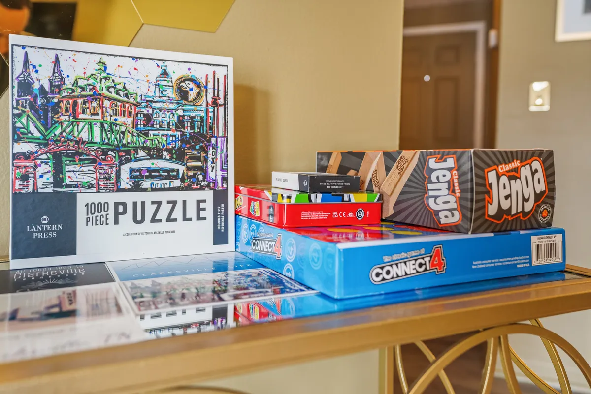 This image features a tabletop setup with a 1000-piece puzzle, Jenga, and Connect 4 game, all invitingly arranged for a family game night. The background and surfaces are neutral, drawing attention to the colorful and family-friendly games.