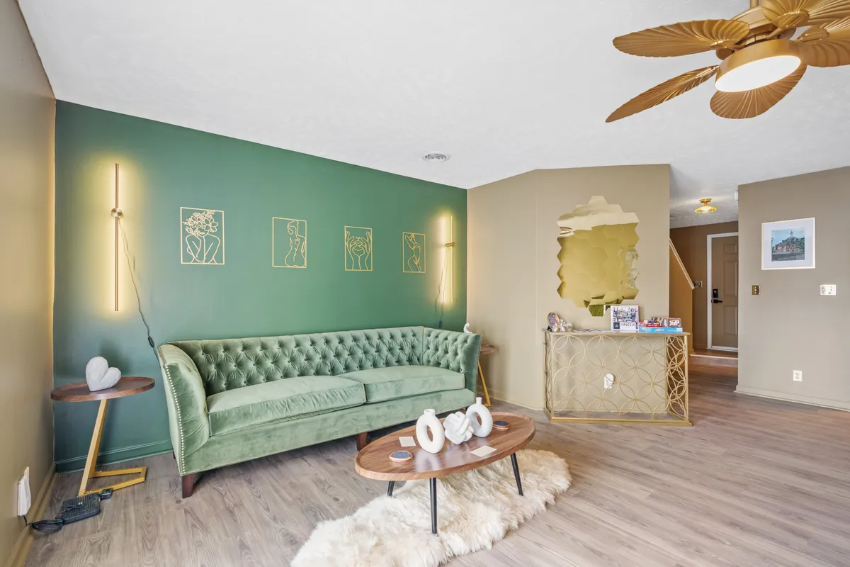 A chic, cozy living area featuring a green velvet sofa, wooden coffee table, golden wall decor, and a large gold mirror. The space is designed for relaxation and socializing, ideal for unwinding after group adventures.